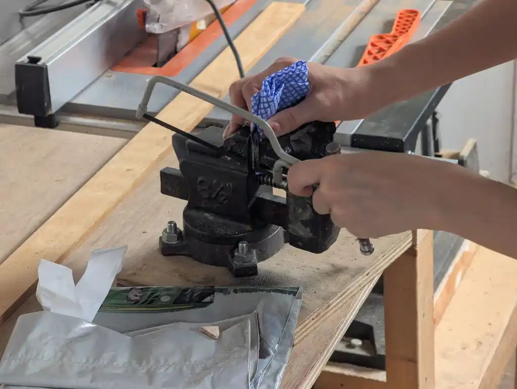 picture of someone sawing a lens in a vice