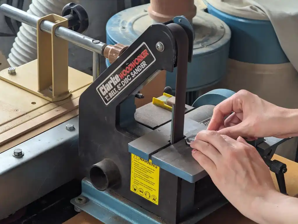 picture of someone using a belt sander to shape a glasses lens