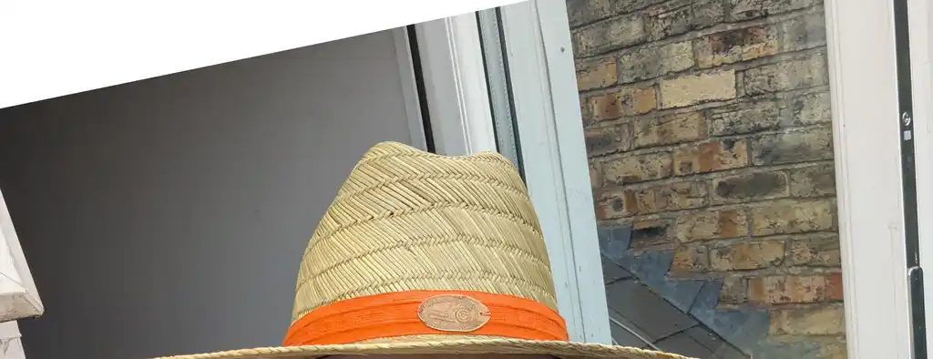 picture of the top of a straw hat, with ribbon and a penny on it