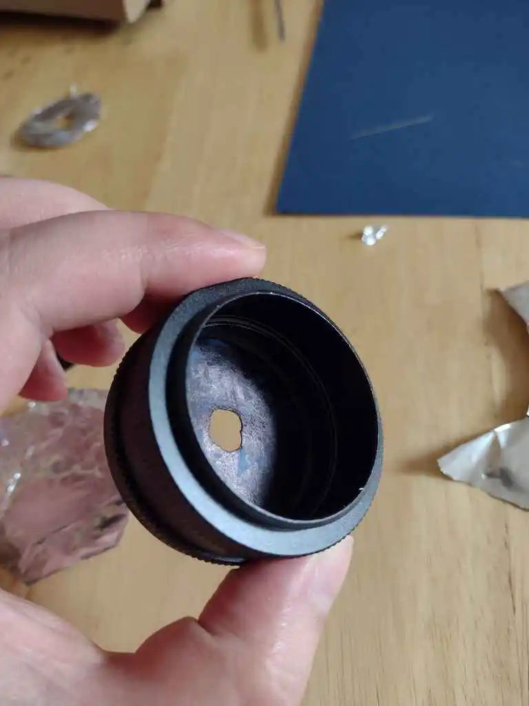 picture of camera lens with small hole bored in the middle, from the back
