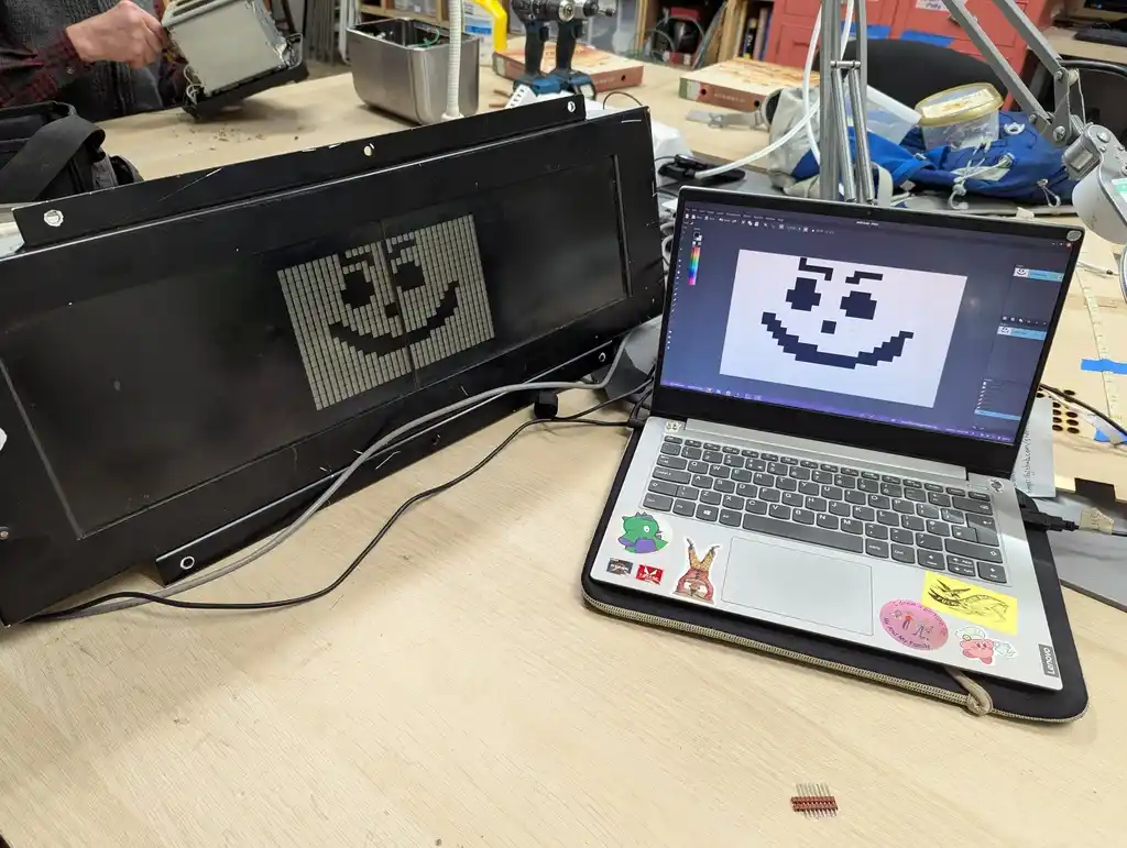 picture of picture on a laptop, and the same picture on a transport sign. picture is of a face