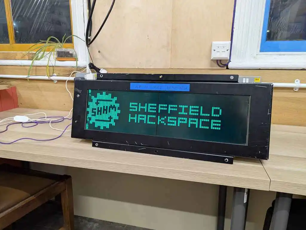 picture of large LCD train sign displaying hackspace logo