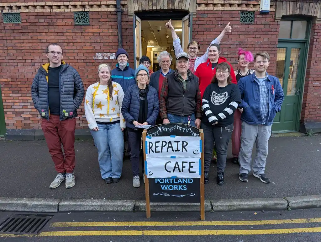 picture of a group of people next to a sign for a repair café
