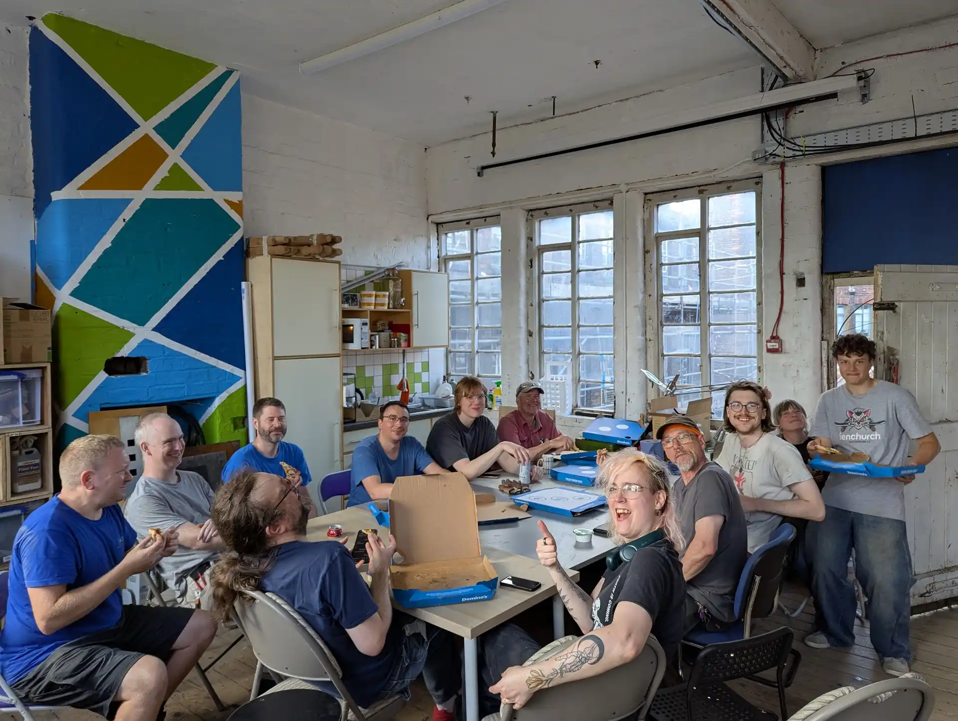 picture of lots of people sat around a table eating pizza